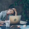 A woman appears stressed while working on laptop.